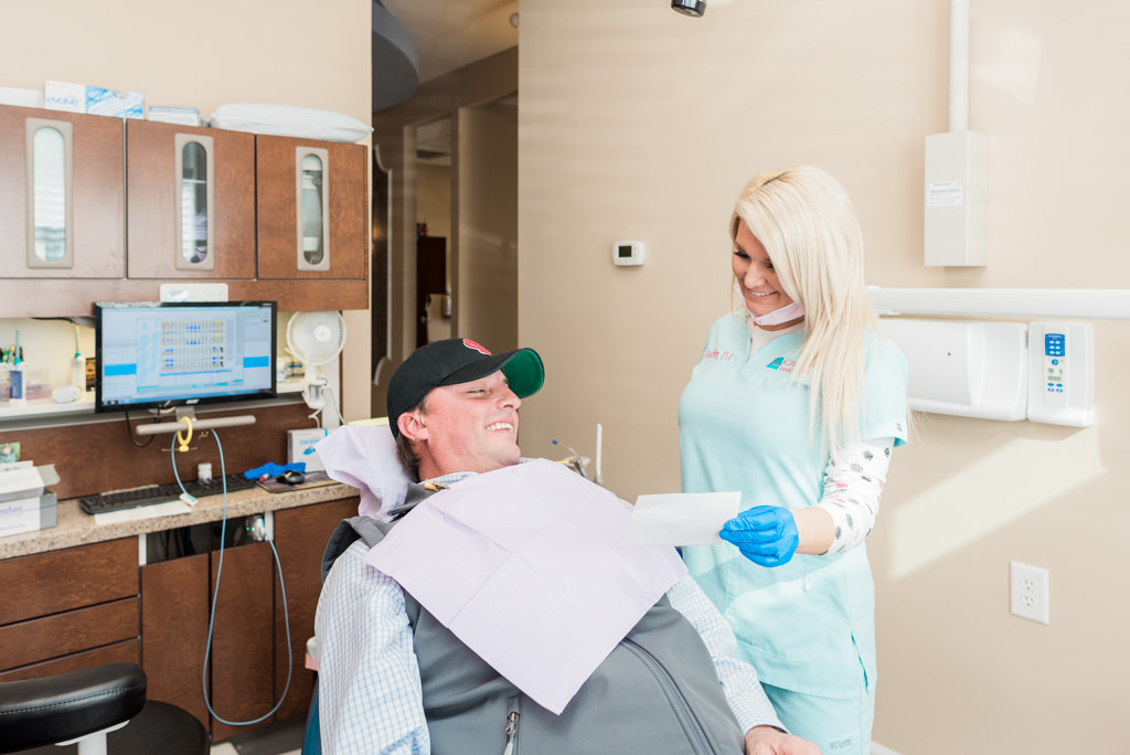 patient in hat looking up and smiling with smiling hygienist