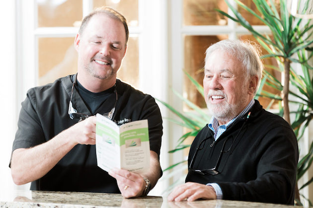 Dr. Davis smiling and showing patient a brochure